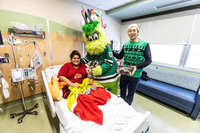 Jason Robertson, Victor E Green, and a patient pose for a picture while smiling as Jason and Viktor give the patient her toys