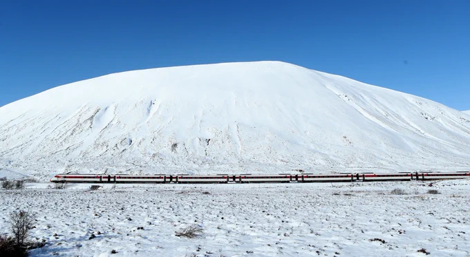 LNER train cutting across the front of a mountain covered in snow