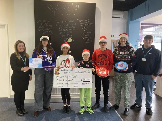 Students handing over a giant cheque for £900 to York Road Project staff.  Students are wearing their own clothes and Christmas hats.