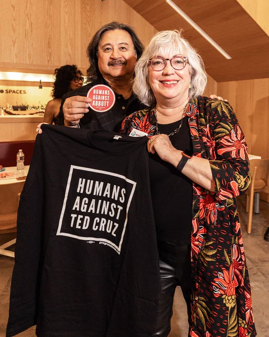 Carl and Denise Wilkerson hold Humans Against Ted Cruz T-shirt — Progress Texas Holiday Party in Dallas