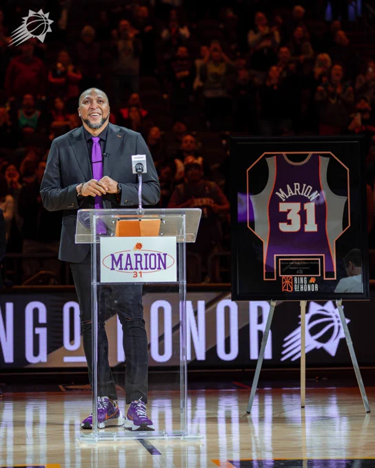 Shawn Marion smiles with his jersey behind him.