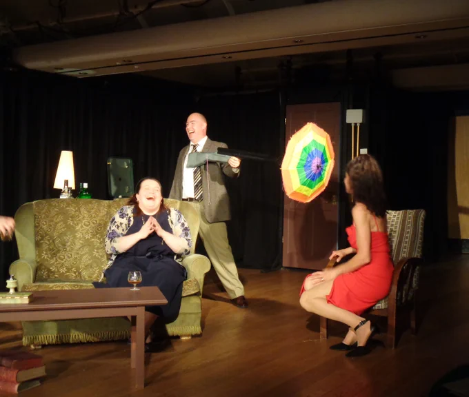 A rainbow umbrell explodes out of a gun and gets a big laugh from the cast of Edward Albee's Who's Afraid of Virginia Woolf?