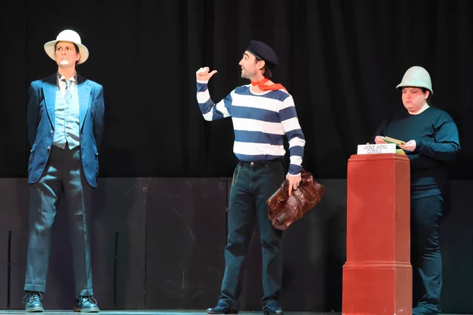 Passepartout, the French valet, talks to the undercover Inspector Fix outside the office of the Hong Kong consul during Phileas Fogg's journey around the world in eighty days.