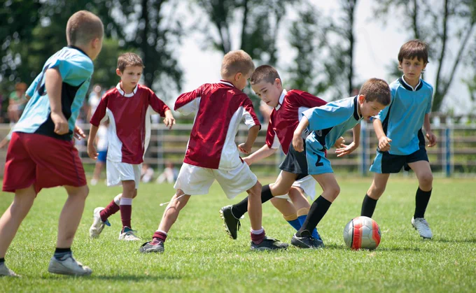 Boys in team uniforms playing soccer
