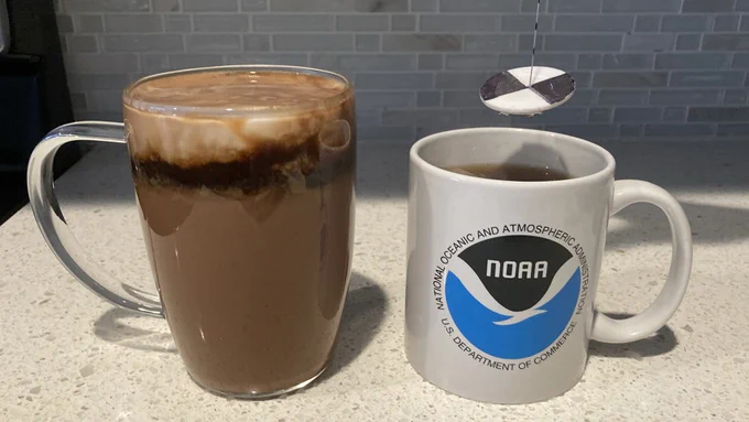 Two cups filled with hot chocolate sit on a counter