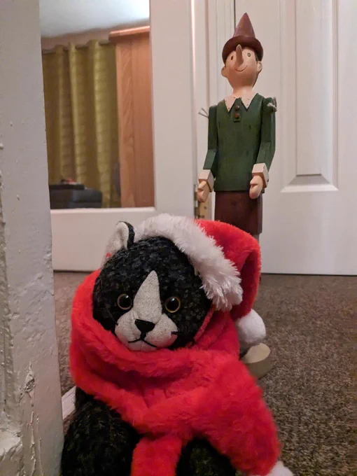 A photo of a toy cat with a Santa hat on.