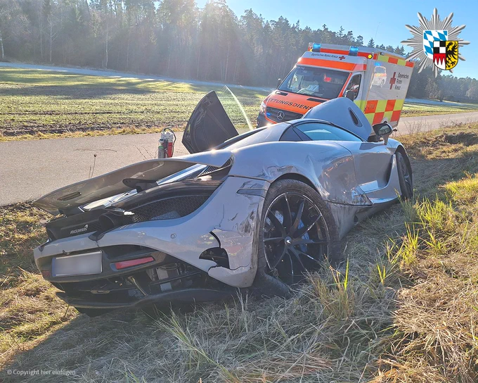 Zeigt ein Bild des verunglückten McLaren. Im Hintergrund ist ein Krankenwagen zu sehen. 