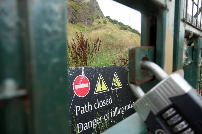 A pad lock with a warning sign and the over-growing path beyond