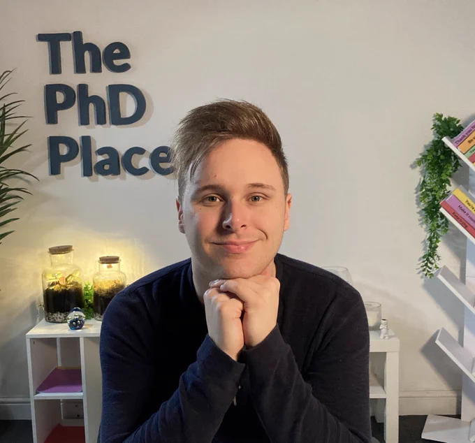 A picture of Nath in front of The PhD Place logo