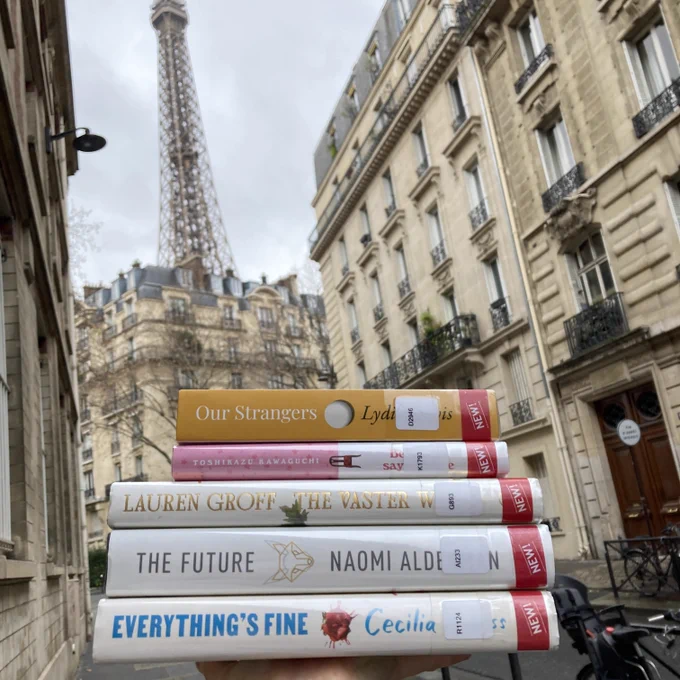 Stack of five books held up in front of the Eiffel Tower.