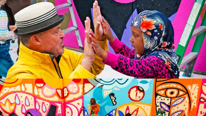 Colorful photo of artist Rafael López and a child clapping hands in front of a mural