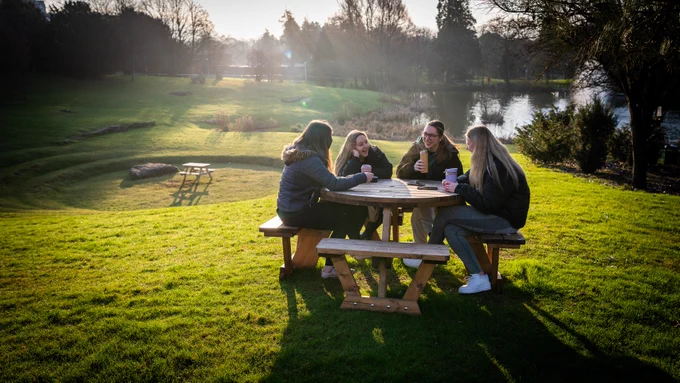 A picture of some friends on a bench by the lake.