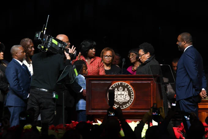 Cherelle Parker being sworn in as the 100th Mayor of Philadelphia by Secretary Marcia Fudge on stage surrounded by family.