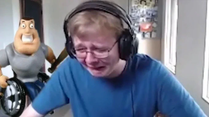 A gamer wearing big black headphones cries at their computer 