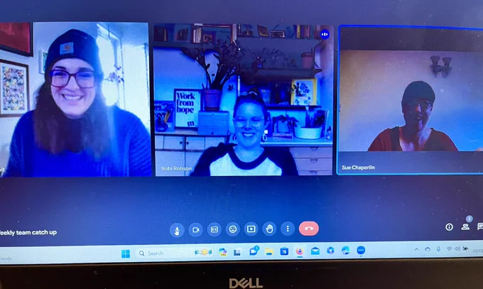 Photo of a laptop. Bobi, Aliya and Sue are having a meeting online. They are smiling.