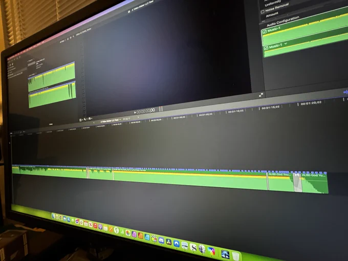 A computer monitor displaying a video editing software interface with multiple audio and video tracks on the timeline.