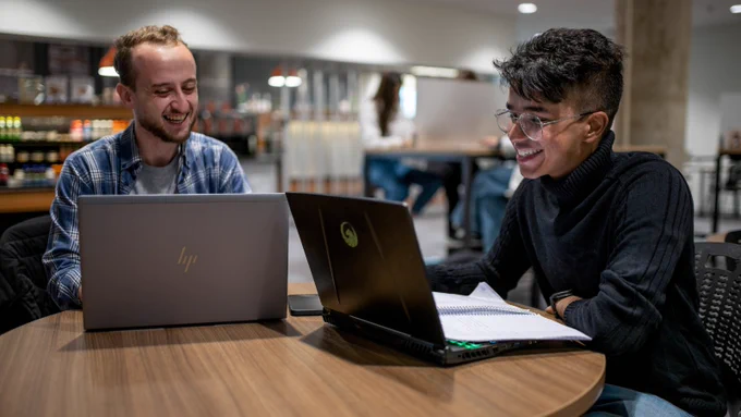 Two Memorial University students use their laptops in the QEII Library Jumping Bean Cafe.