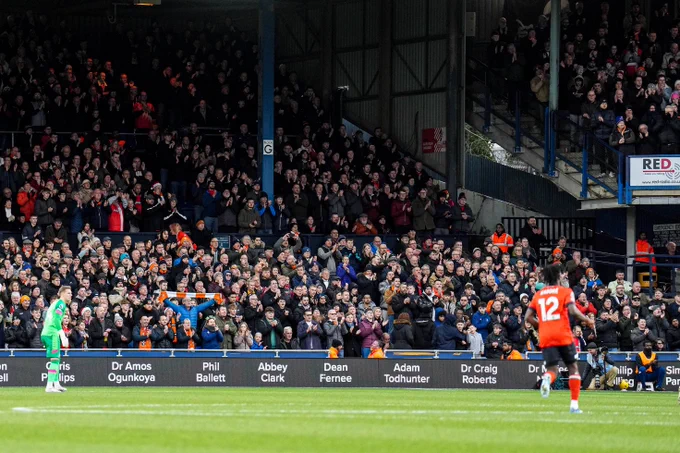 Luton Town fans clapping in the fourth minute for Tom Lockyer, featuring the names of all the people who saved Locks on the LED boards.