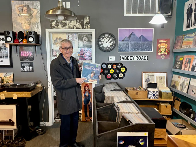 Gov. Evers holds a Patsy Cline record in a record store.