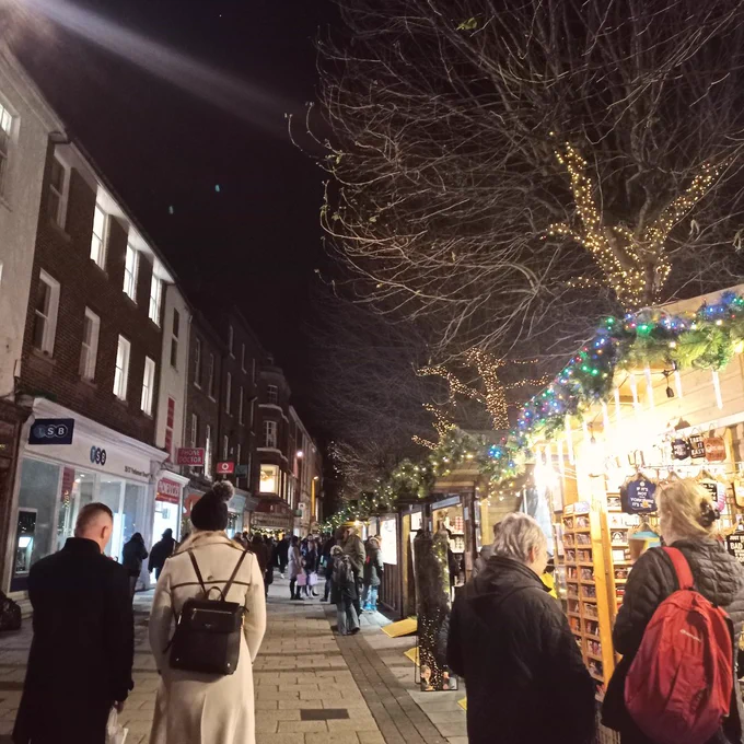 An image of people walking down Parliament Street in York and looking at the Christmas markets at night.
