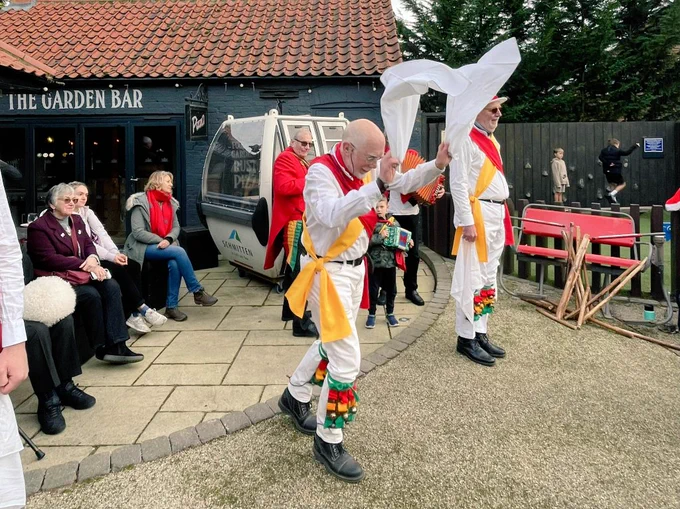 A man morris dancing in a pub garden.