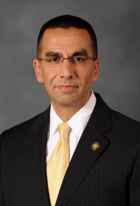 Headshot of Shahram Fard in a black pinstripe suit against a gray background.