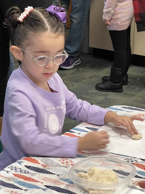Girl playing with white play dough in library