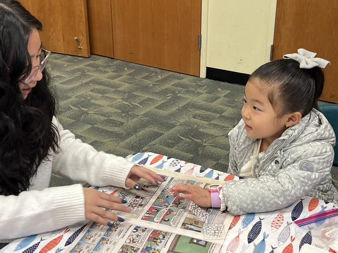 Teen helping child with craft at the library