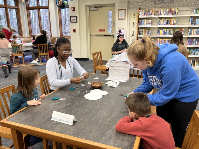 Teens helping children with craft at the library