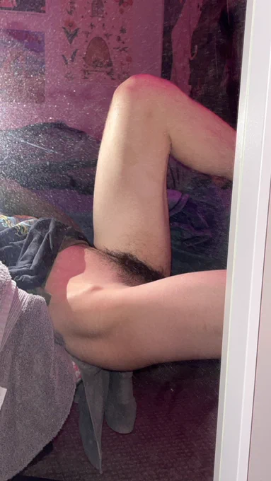 me sitting on the edge of my chair with my legs resting on something not visible (my desk). I'm wearing a grey shirt that's pulled up a bit and nothing else. the picture shows off my muscular legs and thighs, along with my thick bush and muscular ass