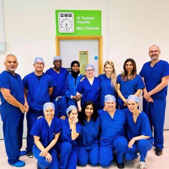 Surgical team gathered to take a picture. They are wearing blue scrubs and smiling.