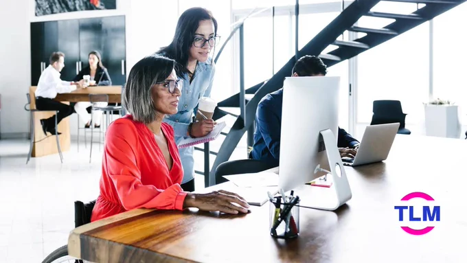Lady in orange blouse in wheelchair at computer