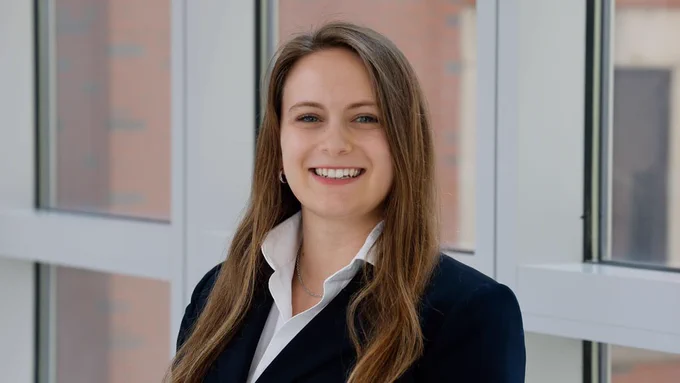 Headshot of Taylor. She is smiling and is wearing a dark blazer with a collared white shirt.
