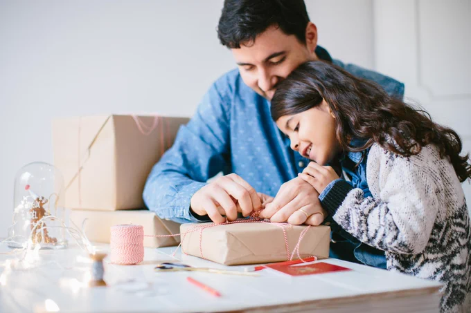Father and daughter wrapping presents.