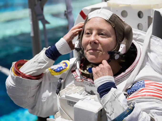 A close-up shot captures NASA astronaut Tracy Dyson adjusting her communication cap during Expedition 71 spacewalk training, pool topside at the Neutral Buoyancy Lab.