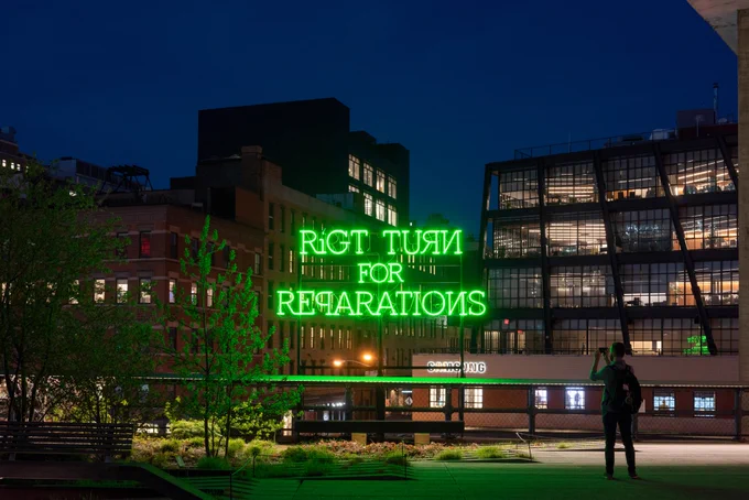 A neon sign of text that reads "RiGT TURN FOR REPARATIONS," at night on the High Line