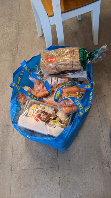 A large bag of surplus food including carrots and bread.
