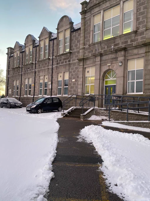 old building with cars parked out the front and a thick layer of snow