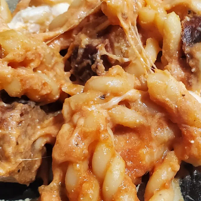 Gemelli pasta with melted: Ricotta cheese, parmesan cheese & mozzarella cheese. Also red pasta sauce & slices of hot Italian sausage.