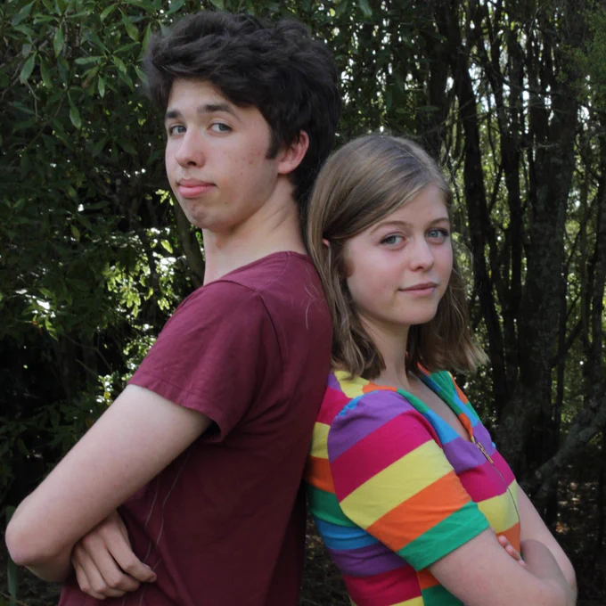 Benedick and Beatrice from NMTD (Much Ado About Nothing) the webseries, lean back against each other. Arms crossed.