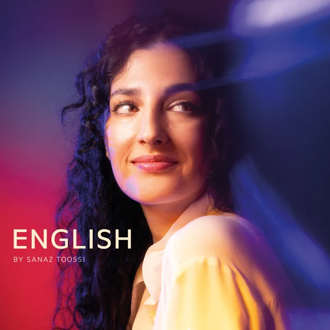 Sanaz Toossi looking away from camera to the right in front of a purple and red faded background, with flashes of light to the right. On the left, white text reads: English, by Sanaz Toossi.