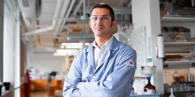 Emory Chemistry Professor William Wuest stands with his arms crossed in a blue lab coat over a white dress shirt