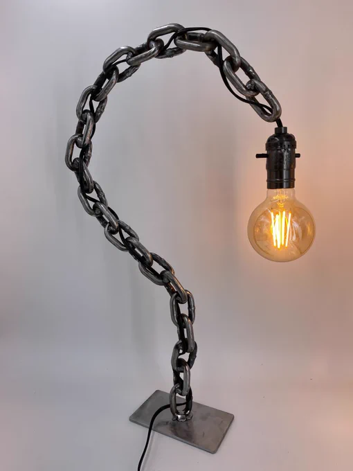Welded lamp with a chainlink stem supporting a large light bulb.