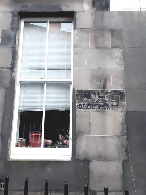 Remains of a sign painted on a wall next to a window