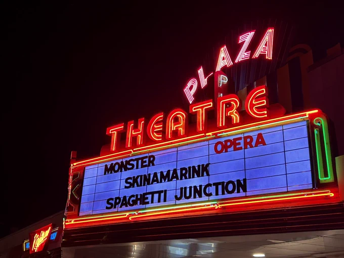 Picture of a glowing movie theater marquis at night with Plaza Theatre in the big red neon lights. The films on the marquee are monster opera, Skinamarink, and Spaghetti Junction.