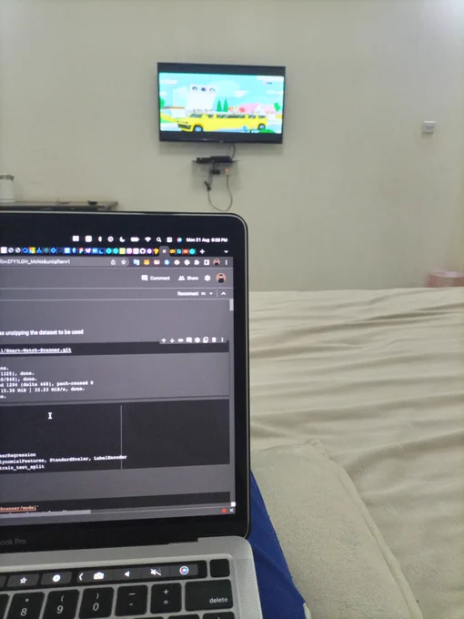Laptop to the left with a TV mounted to the wall in front 
