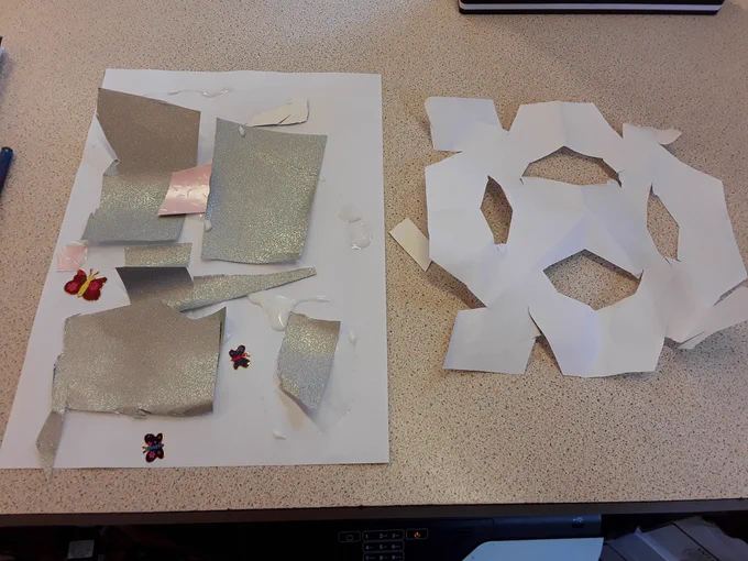 Photo showing a snowflake cut out of paper and stickers and card stuck on a piece of paper 