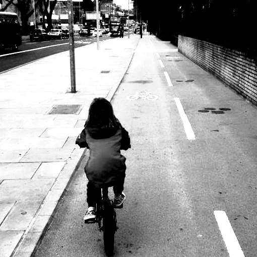 child cycles on safe cycle track beside main road