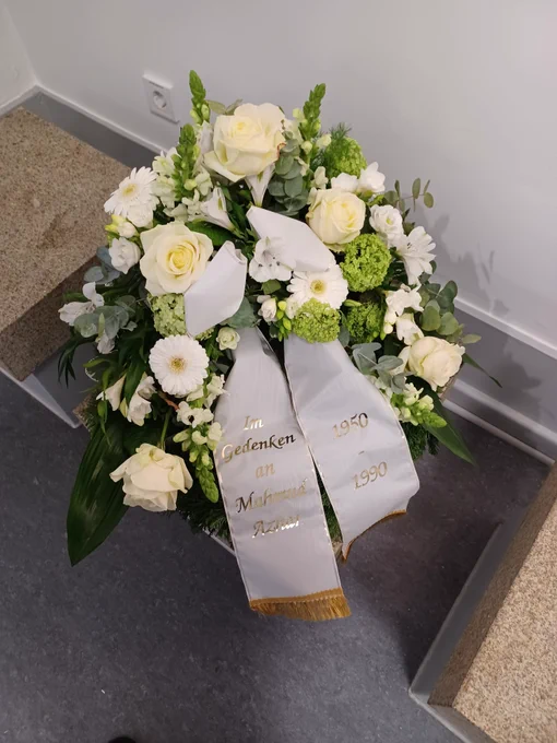 Gedenkblumenkranz mit einer Scherpe auf der steht "In Gedenken an Mahmud Azhar, 1950 - 1990.