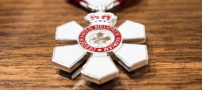 Order of Canada medal sits on wooden table. 